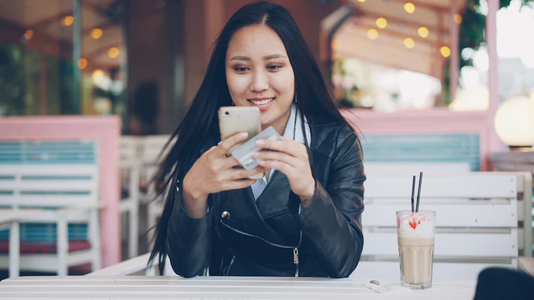 Customer checking a smartphone while seated at an outdoor cafe