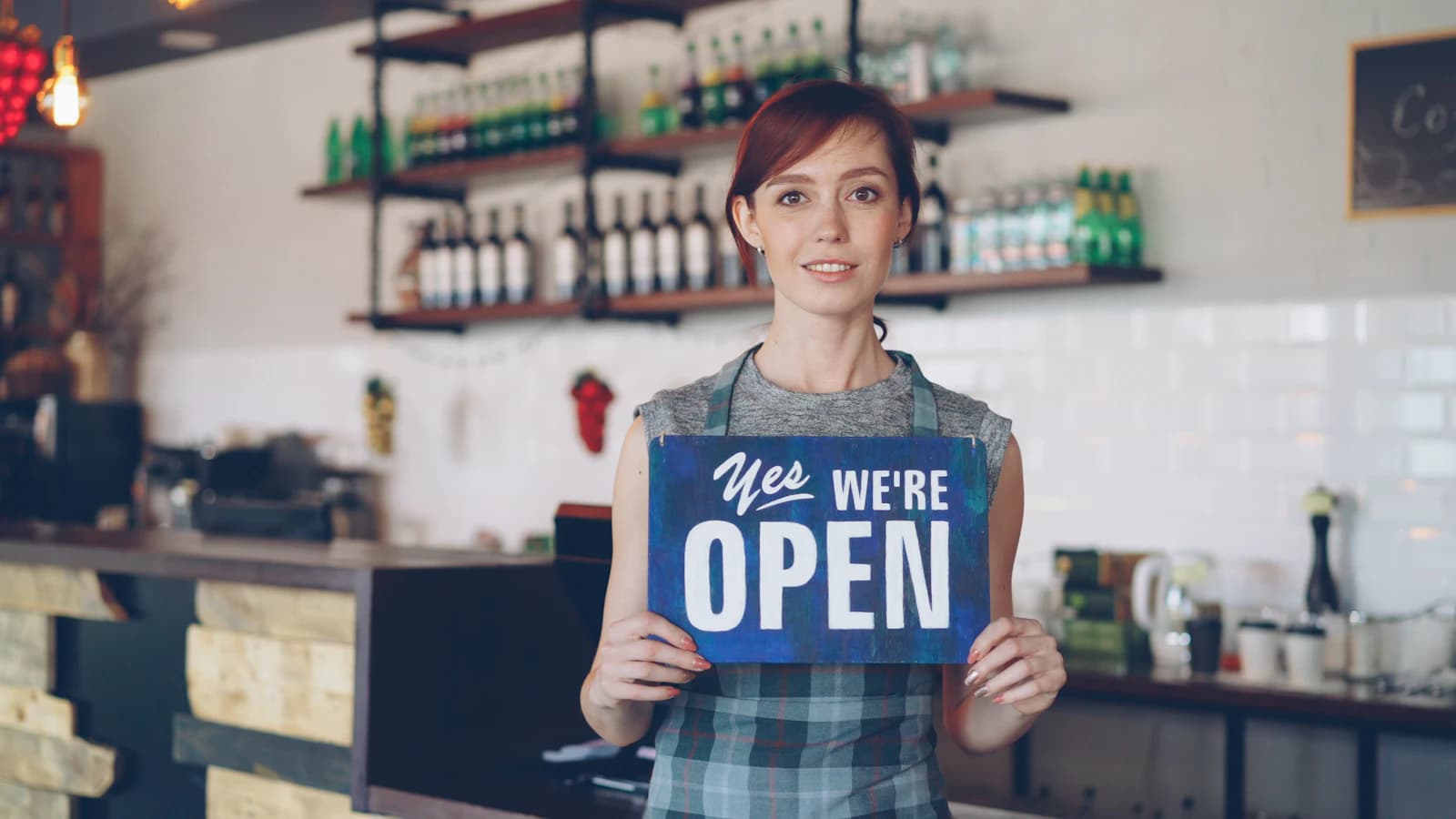 Coffee shop owner welcoming customers inside her storefront